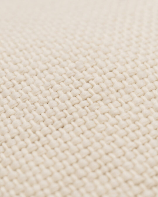 Detalhes da textura e tecido de uma almofada quadrada feita a mão em tear com lã merino cor cru natural.